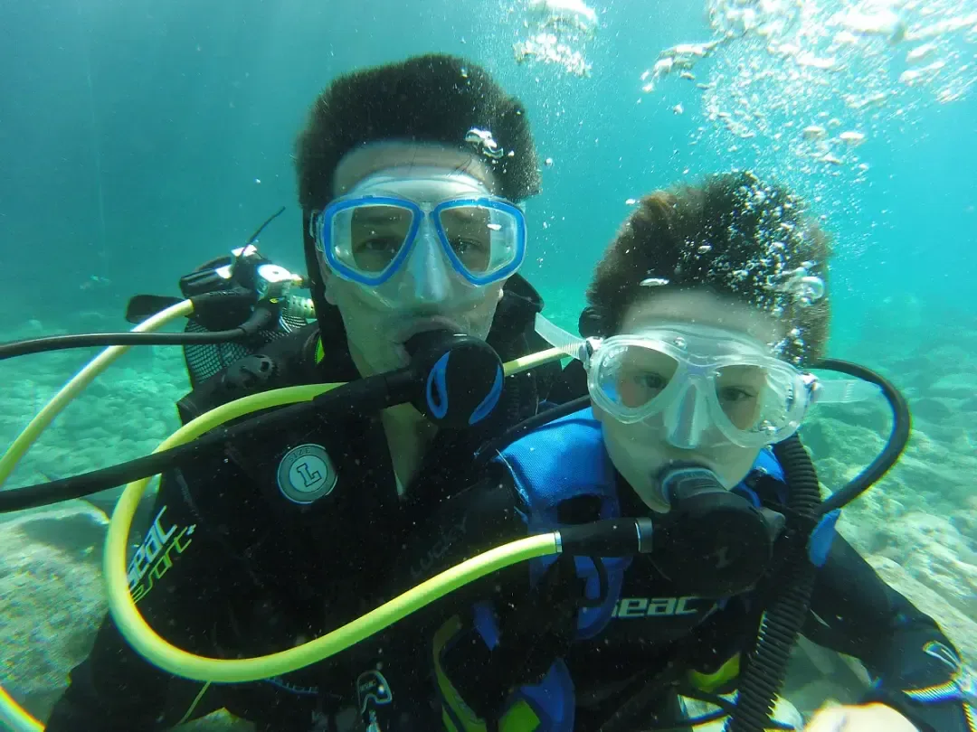 Smiling young diver swimming toward the camera in the calm, clear water